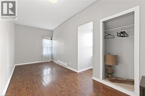 Room featuring wood-finish flooring, light grey painted walls, and white baseboards - 238-242 King Street E, Hamilton, ON 