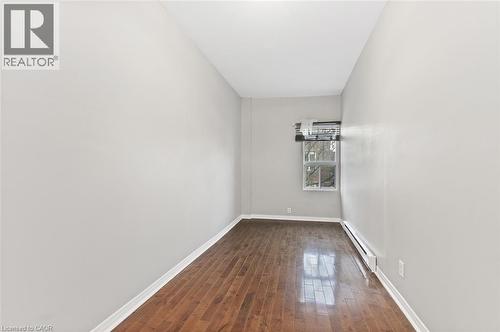Windowed room featuring wood-finish flooring, light gray wall paint, and white baseboards - 238-242 King Street E, Hamilton, ON 