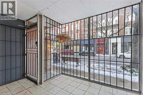 Entryway featuring ceramic tile flooring, a decorative pendant light fixture, and floor-to-ceiling windows with security bars - 238-242 King Street E, Hamilton, ON 