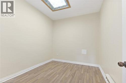 Room with wood-finish flooring, white baseboards, and a ceiling skylight - 238-242 King Street E, Hamilton, ON 