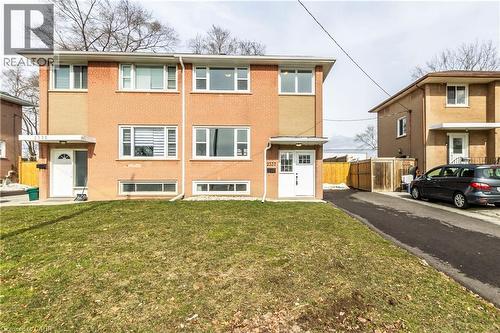 Brick and stucco exterior featuring multiple windows, a front lawn, and a paved driveway - 2337 Barclay Road, Burlington, ON - Outdoor