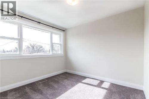Spacious room with large windows, neutral wall color, dark gray carpet, white baseboards, and a ceiling-mounted light fixture - 2337 Barclay Road, Burlington, ON - Indoor Photo Showing Other Room