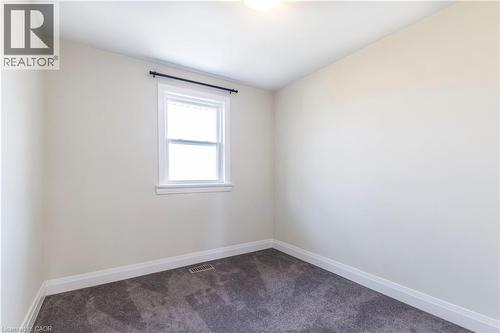 Neutral-toned room featuring a single window with white trim, a black curtain rod, and dark gray carpeting - 2337 Barclay Road, Burlington, ON - Indoor Photo Showing Other Room