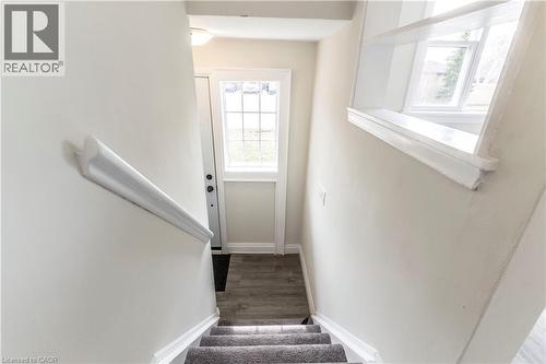 Carpeted staircase with white trim, wood-finish flooring, and natural light from a glass-paned door - 2337 Barclay Road, Burlington, ON - Indoor Photo Showing Other Room