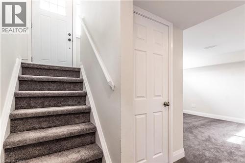 Carpeted staircase featuring a white handrail, leading to a white paneled door with a frosted glass insert - 2337 Barclay Road, Burlington, ON - Indoor Photo Showing Other Room