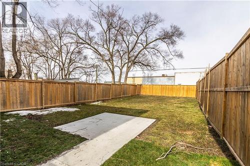 Expansive grassy yard area featuring a concrete patio pad and full wood privacy fencing - 2337 Barclay Road, Burlington, ON - Outdoor With Backyard