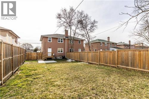 Expansive outdoor space featuring a wooden privacy fence, a ground-level patio, and a back entrance with a wood deck and staircase - 2337 Barclay Road, Burlington, ON - Outdoor With Backyard With Exterior