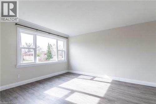 Spacious room featuring a large multi-pane window, wood-finish flooring, neutral wall tones, white trim, and crown molding - 2337 Barclay Road, Burlington, ON - Indoor Photo Showing Other Room