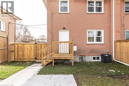 Brick exterior featuring a wooden deck with railing, a white exterior door, and multiple white-framed windows - 2337 Barclay Road, Burlington, ON - Outdoor With Exterior