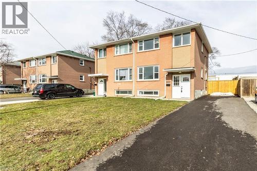 Brick exterior featuring multiple windows, a white entry door, and an asphalt driveway - 2337 Barclay Road, Burlington, ON - Outdoor