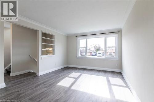 Spacious room featuring wood-finish flooring, a large window, built-in shelving, white baseboards, and crown molding - 2337 Barclay Road, Burlington, ON - Indoor Photo Showing Other Room