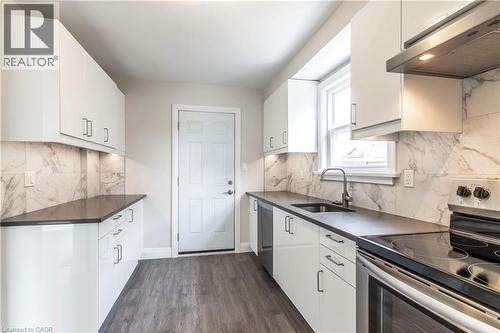 Contemporary kitchen featuring white cabinetry, dark countertops, and a full-height marble-look backsplash - 2337 Barclay Road, Burlington, ON - Indoor Photo Showing Kitchen