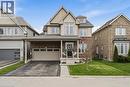Two-story residence featuring a brick and siding exterior, a covered porch entry, a two-car garage, and an asphalt driveway - 42 Yager Drive, Binbrook, ON  - Outdoor With Facade 
