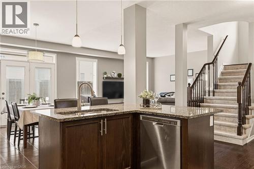 Kitchen island featuring a stainless steel dishwasher, granite countertop, and integrated sink with a gooseneck faucet - 42 Yager Drive, Binbrook, ON - Indoor Photo Showing Kitchen