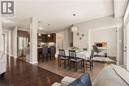 Open-concept living area featuring a dining space with a contemporary pendant light, a functional kitchen with dark wood-finish cabinetry and stainless steel appliances, and a dedicated room accessibl - 42 Yager Drive, Binbrook, ON - Indoor