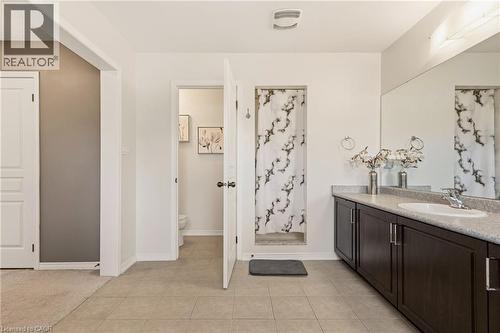 Bathroom featuring a dual-sink vanity with dark wood cabinetry, a light-toned countertop, and an integrated mirror - 42 Yager Drive, Binbrook, ON - Indoor Photo Showing Bathroom