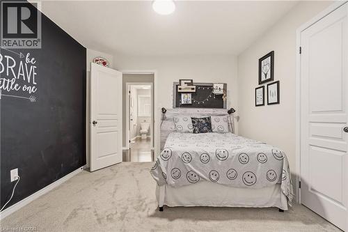 Carpeted bedroom featuring a chalkboard accent wall, white trim, and a three-panel interior door - 42 Yager Drive, Binbrook, ON - Indoor Photo Showing Bedroom