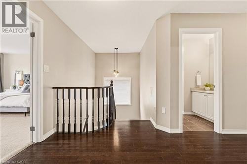 Upper-level landing featuring dark wood-finish flooring, a contemporary black spindle railing, and a window with blinds - 42 Yager Drive, Binbrook, ON - Indoor Photo Showing Other Room