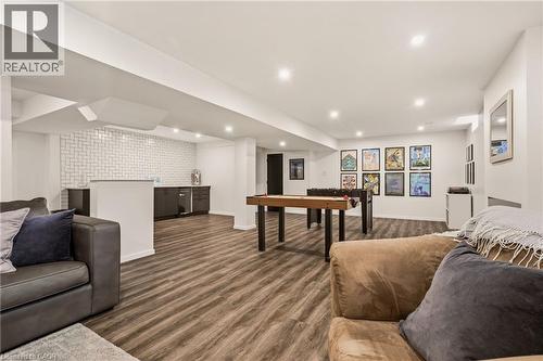Spacious lower level featuring wood-finish flooring, recessed lighting, and a built-in wet bar with dark cabinetry and a tile backsplash - 42 Yager Drive, Binbrook, ON - Indoor