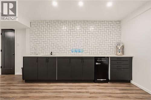 Wet bar featuring a herringbone tile backsplash, integrated sink, and dark cabinetry - 42 Yager Drive, Binbrook, ON - Indoor Photo Showing Other Room