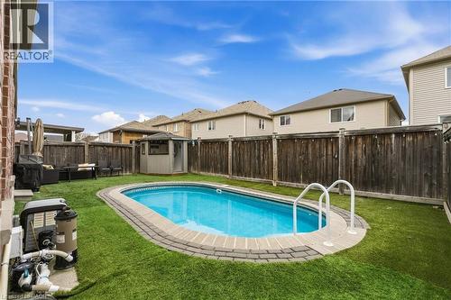 Oval-shaped in-ground salt water pool with paver surround, artificial turf, and a privacy fence - 42 Yager Drive, Binbrook, ON - Outdoor With In Ground Pool With Backyard