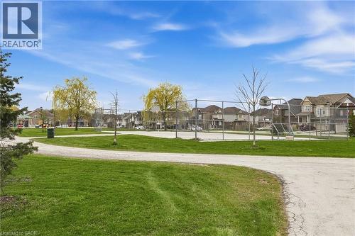 Outdoor recreational space featuring a basketball court, fenced perimeter, and a walking path surrounded by green grass - 42 Yager Drive, Binbrook, ON - Outdoor With View
