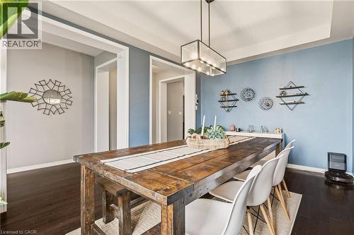 Dining area featuring dark wood-finish flooring and a contemporary linear chandelier - 42 Yager Drive, Binbrook, ON - Indoor Photo Showing Dining Room