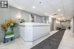 Modern reception area featuring a white desk, recessed lighting, and sconce fixtures - 