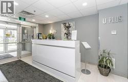 Bright reception area featuring a white high-gloss counter, recessed ceiling lighting, and light tile flooring - 