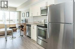 Modern kitchen featuring stainless steel appliances including a refrigerator, oven with cooktop, microwave, and dishwasher - 