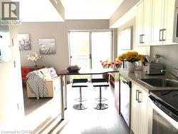 Kitchenette featuring white cabinetry with brushed nickel hardware, a stainless steel sink, and light-toned countertops - 