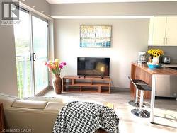 Open-concept living area featuring a full-width sliding glass door to the exterior, wood-finish flooring, recessed lighting, and a kitchen island with seating - 