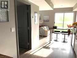 Open-concept living area featuring light-toned wood-finish flooring, a sliding glass door, an integrated breakfast bar with seating, and white kitchen cabinetry - 