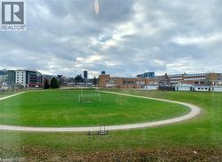 Expansive green space featuring a large sports field with goalposts and a perimeter walking path - 