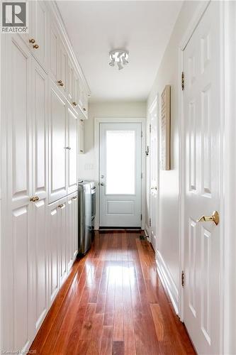 Hallway featuring extensive white cabinetry with gold-toned hardware, rich wood-finish flooring, and a white paneled door with frosted glass - 1577 Old Spar Court, Mississauga, ON - Indoor Photo Showing Other Room
