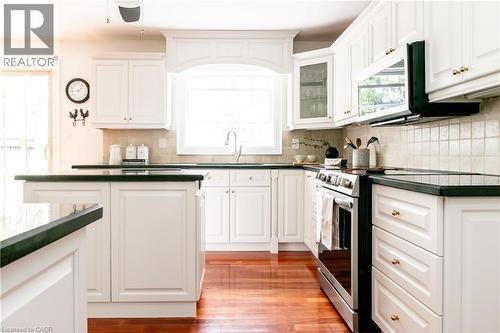 Kitchen featuring white cabinetry, dark countertops, a tile backsplash, and wood-finish flooring - 1577 Old Spar Court, Mississauga, ON - Indoor Photo Showing Kitchen With Upgraded Kitchen