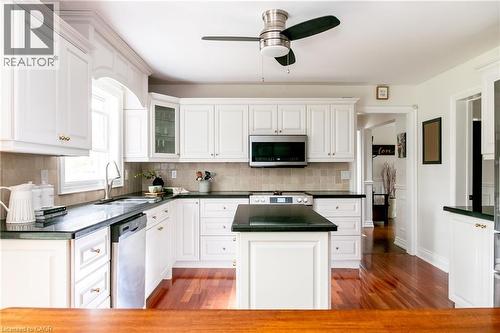 Kitchen featuring white cabinetry, dark countertops, a central island, stainless steel appliances, and wood-finish flooring - 1577 Old Spar Court, Mississauga, ON - Indoor Photo Showing Kitchen