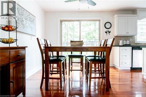 Open-concept dining area featuring wood-finish flooring, a sliding glass door, white baseboards, a ceiling fan, and white kitchen cabinetry with dark countertops - 1577 Old Spar Court, Mississauga, ON - Indoor Photo Showing Dining Room