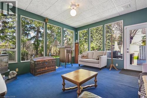 Room featuring floor-to-ceiling windows, blue carpeting, green paneling, white ceiling, and a white exterior door with glass insert - 2117 Edinburgh Drive, Burlington, ON - Indoor Photo Showing Other Room