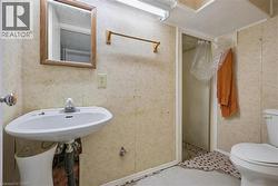 Bathroom featuring a wall-mounted sink, framed mirror, and a shower enclosure - 