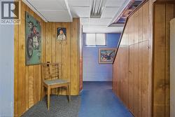 Finished lower level space featuring wood paneling, blue flooring, and a drop ceiling - 