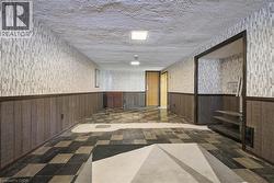 Spacious room featuring patterned wallpaper, wood-panel wainscoting, and a checkered floor - 