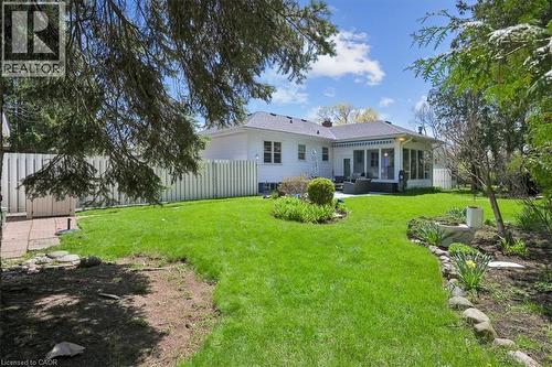 Expansive green lawn with established landscaping beds, a sunroom extension, and a white picket fence - 2117 Edinburgh Drive, Burlington, ON - Outdoor