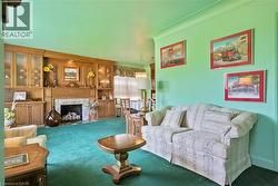 Living area featuring a stone surround fireplace with a wood mantle, flanked by built-in wood cabinetry with glass-front display cases - 