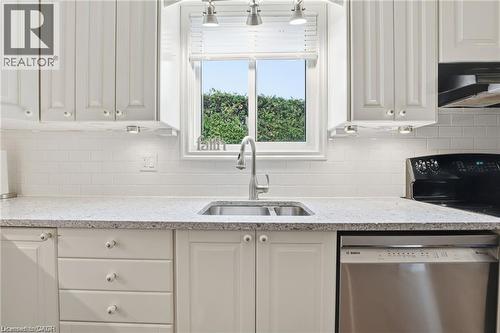 White kitchen with quartz counters and view to backyard - 668 Tomahawk Crescent, Ancaster, ON - Indoor Photo Showing Kitchen With Double Sink