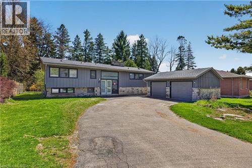 Contemporary residence featuring a detached two-car garage, stone and vertical siding exterior, and a paved driveway - 515 Bobbybrook Drive, London, ON - Outdoor