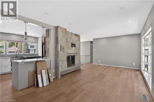 Open-concept living space featuring wood-finish flooring, a stone-clad fireplace, and recessed lighting - 515 Bobbybrook Drive, London, ON - Indoor With Fireplace