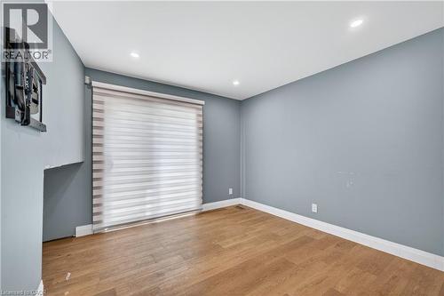 Sliding glass door with horizontal banded shade, recessed lighting, wood-finish flooring, and light blue wall tones - 515 Bobbybrook Drive, London, ON - Indoor Photo Showing Other Room