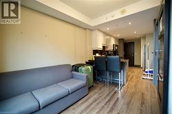Open-concept living space with wood-finish flooring, a contemporary kitchen, recessed lighting, and a kitchen island with seating - 