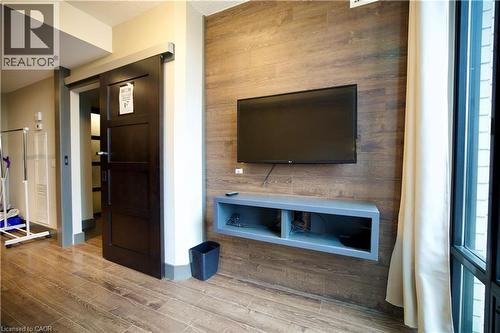 Interior space featuring wood-finish flooring, a contemporary dark wood barn door, and a full-height window with light-toned drapes - 330 Phillip Street Unit# S605, Waterloo, ON - Indoor Photo Showing Other Room